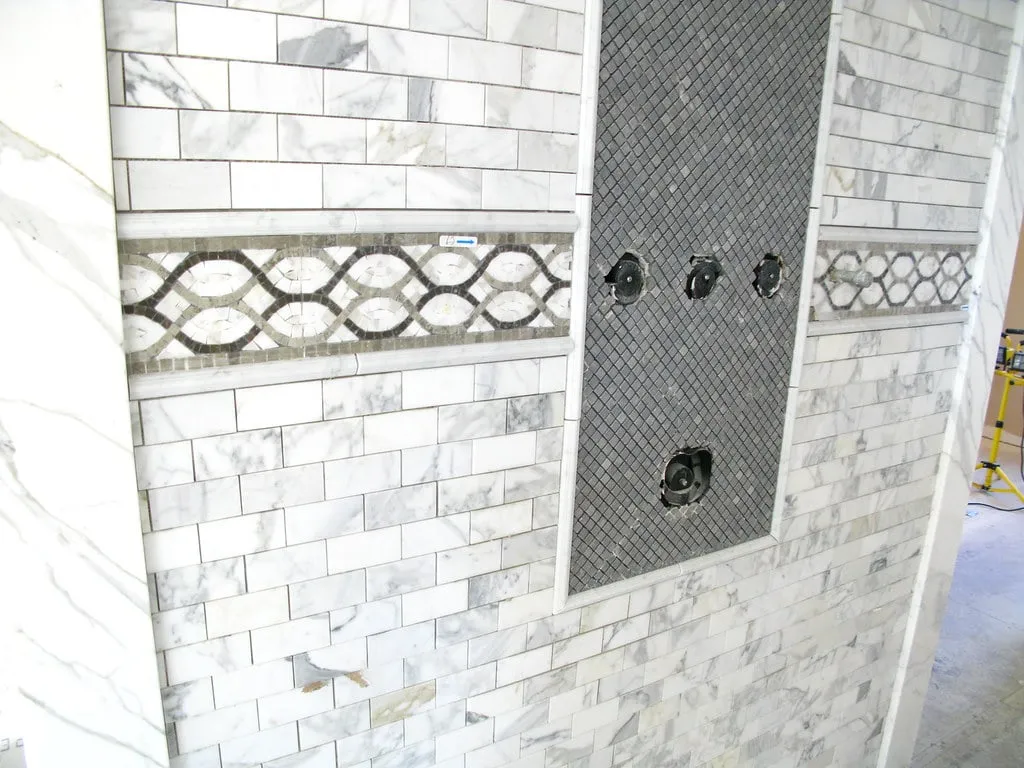 Marble subway tile shower with a mosaic accent band